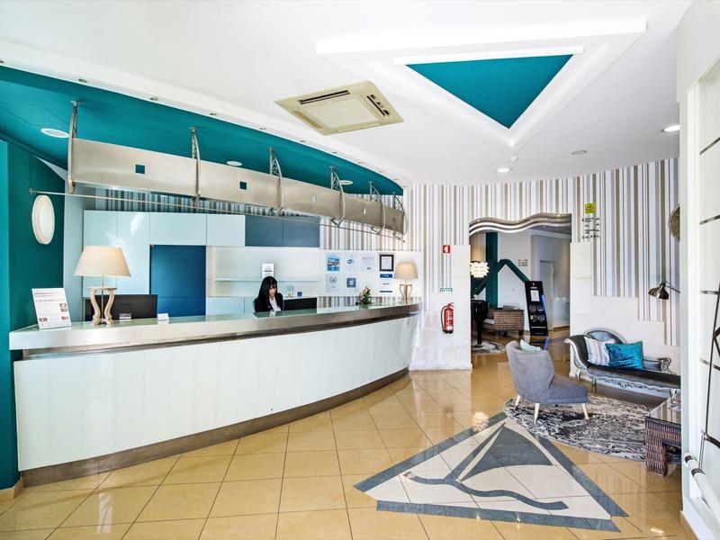 Moderner Empfangsbereich mit blau-weißer Farbgestaltung, Tresen, Sitzgelegenheiten und dekorativem Teppich.