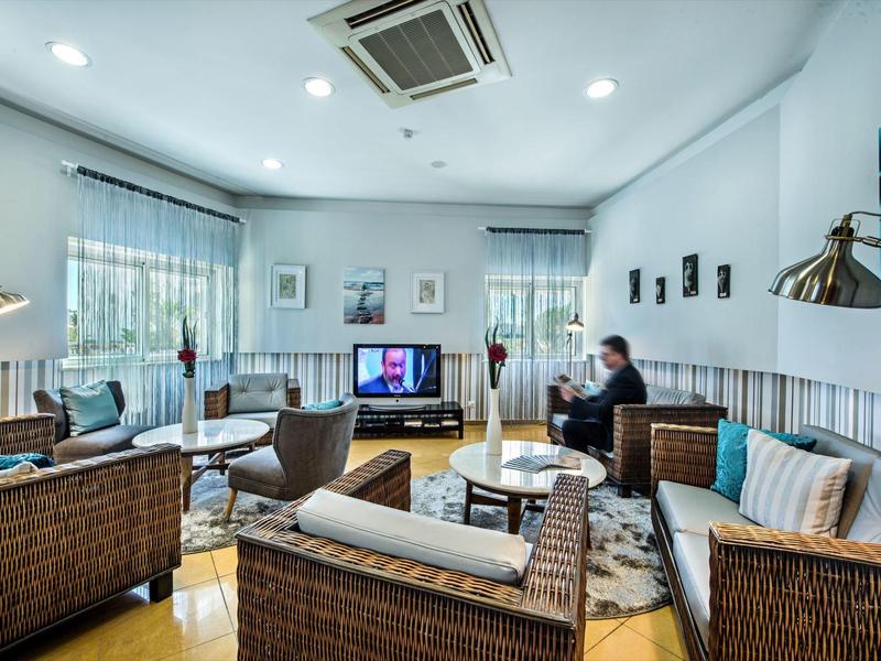 Moderne, helle Lounge mit Korbsesseln, Holzboden, mehreren Sitzgruppen und großer Klimaanlage.