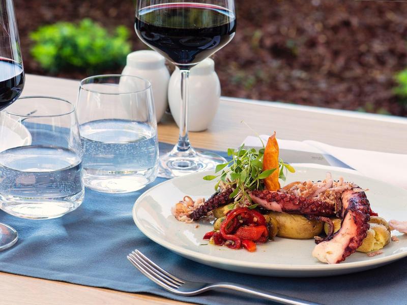 Gurmánské jídlo s mořskými plody a červeným vínem na venkovním stole.