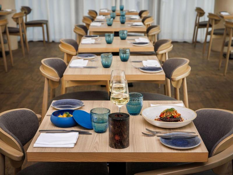 Elegantní jídelní stůl v restauraci se servisem talířů a sklenic.