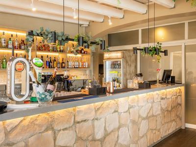 Espace bar avec comptoir en pierre et large choix de boissons dans un hôtel moderne.