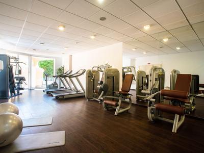 Heller Fitnessraum mit Trainingsgeräten und Laufband in einem Hotel.