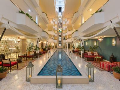 Intérieur d'hôtel avec une longue piscine d'eau, des espaces de sièges et une ambiance moderne.