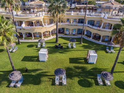 Vue d'un hôtel à plusieurs étages avec des chaises longues et une pelouse verte avec des palmiers