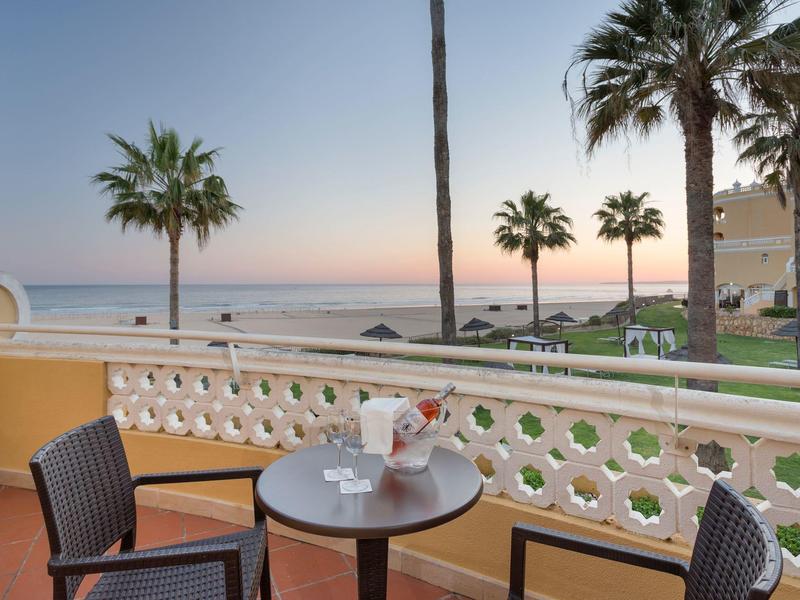 Balcon avec table, chaises et vue sur la mer au coucher du soleil dans un hôtel de vacances.