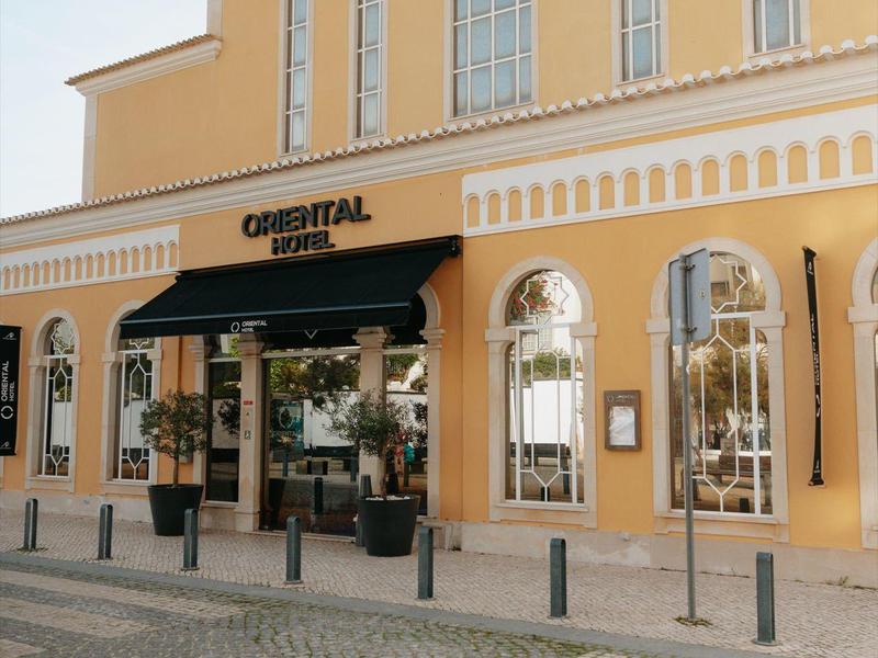 Façade d'un bâtiment jaune avec un restaurant nommé Oriental avec de grandes fenêtres et une entrée noire