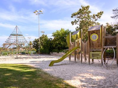 Aire de jeux avec tour d'escalade, toboggan et pyramide en filet ensoleillée