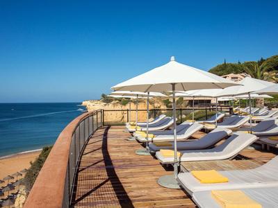 Terrasse ensoleillée avec transats et parasols blancs surplombant la mer