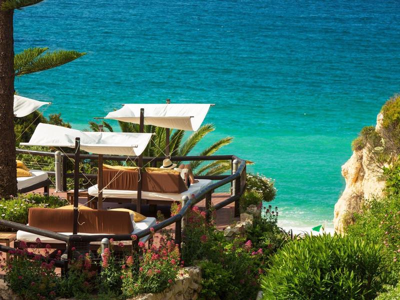 Terrasse avec tables et parasols au-dessus d'une mer turquoise