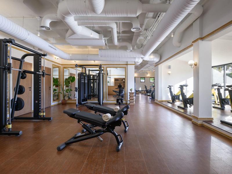 Salle de sport moderne avec bancs de musculation, machines de musculation et grands miroirs
