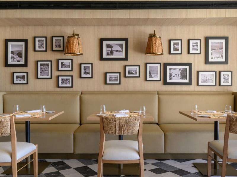 Salle à manger moderne avec sièges beige rembourrés et nombreuses photos encadrées au mur.