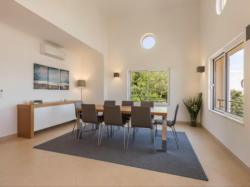 Salle à manger moderne avec grande table, six chaises et pièce lumineuse.
