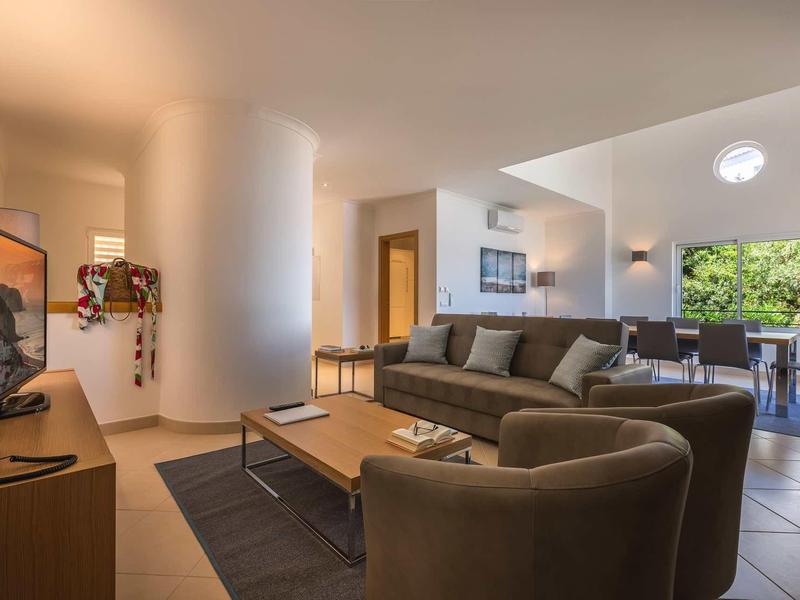 Salon moderne avec canapés confortables et vue sur la salle à manger avec grandes fenêtres.