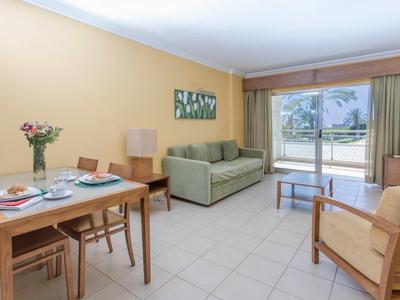 Lichte woonruimte met eettafel, bank en terras met uitzicht op het zwembad.