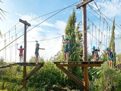 Mensen die obstakels overwinnen in een klimpark op een zonnige dag.
