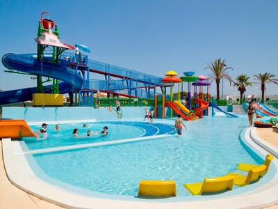 Waterpark met meerdere zwembaden, glijbanen en ligstoelen bij zonnig weer.