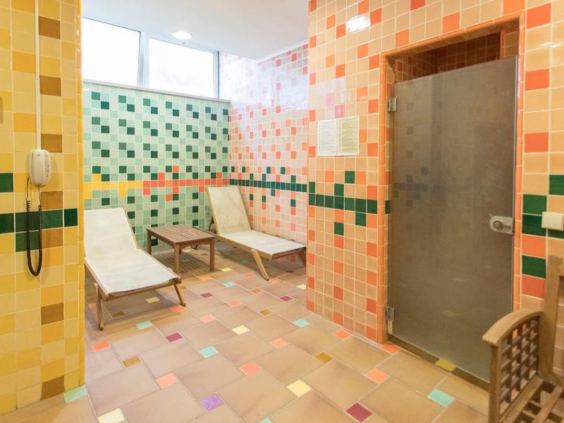 Kleurrijke wellnessruimte met ligstoelen en een afsluitbare glazen deur.