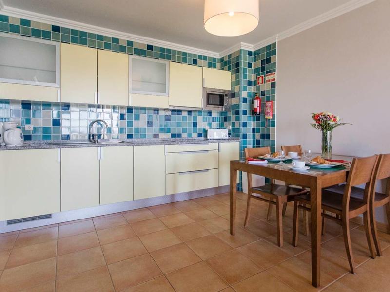 Moderne keuken met kleurrijke tegels en een houten tafel in een hotelappartement.