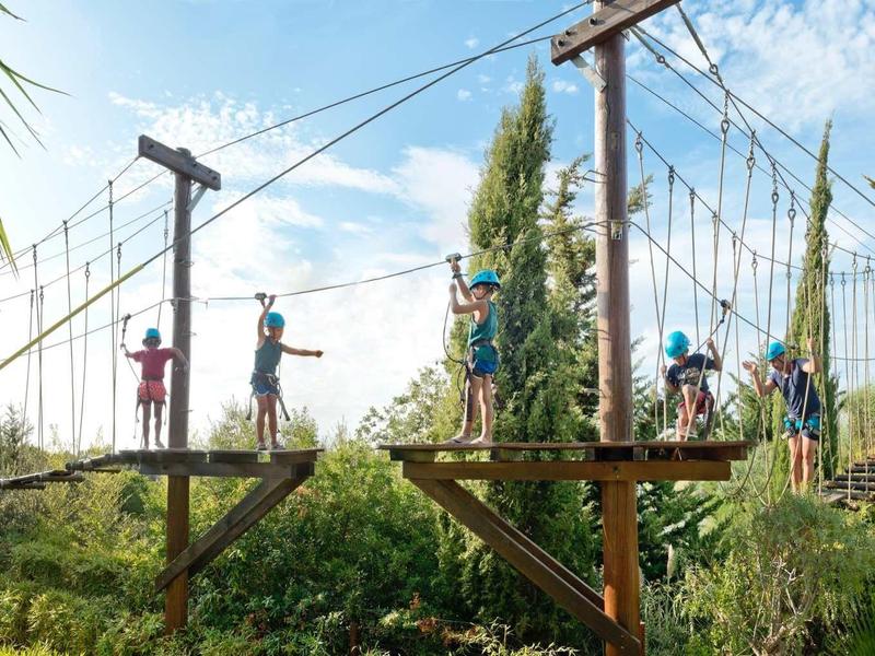 Mensen die obstakels overwinnen in een klimpark op een zonnige dag.