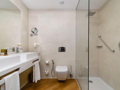 Moderne badkamer met inloopdouche, toilet en dubbele wastafel in neutrale tinten.