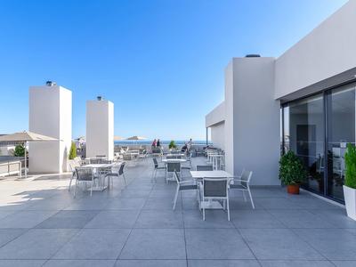 Moderne hotel dakterras met zitgedeeltes en heldere blauwe lucht.