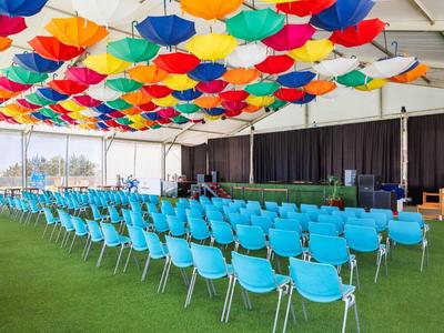 Vergaderruimte met blauwe stoelen en kleurrijke paraplu's aan het plafond.
