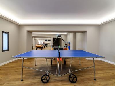 Ein blaues Tischtennisplatte in einem hellen Raum mit Holzboden und weißen Wänden.