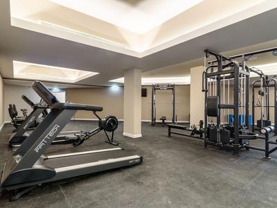 Moderner Fitnessraum mit Laufbändern, Rudergerät und Kraftstationsgeräten in neutralem Raum.