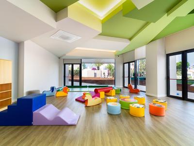 Moderne speelruimte met kleurrijke zitzakken en klimtrappen, grote ramen, heldere sfeer.