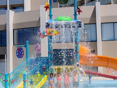 Kleurrijke glijbaan met spattend water voor hoog gebouw in vakantieoord.