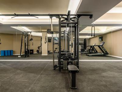 Moderner Fitnessraum mit Kraftgerät, Laufband und großen Spiegeln an den Wänden.