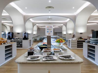 Een grote, moderne ontbijtruimte met buffet en gedekte tafels.