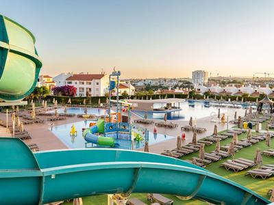 Waterpark met glijbanen, groot zwembad en ligstoelen bij zonsondergang