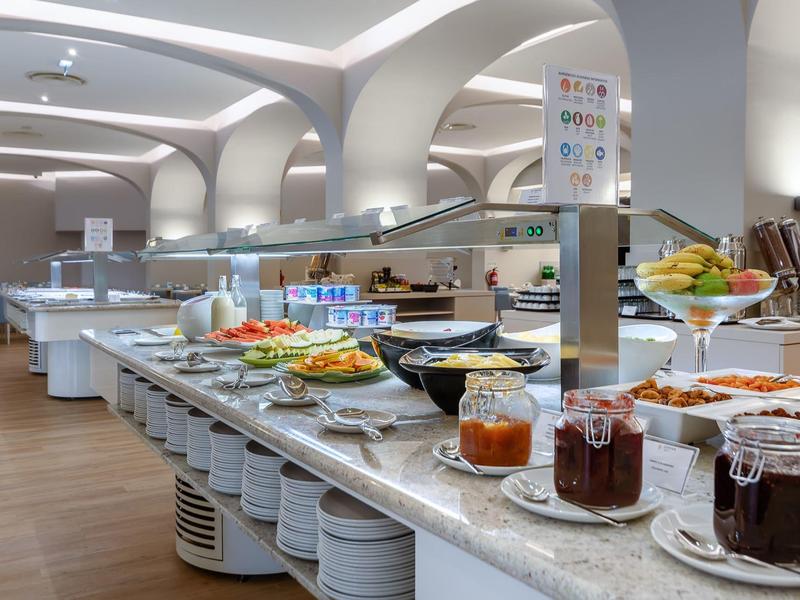 Buffet met jam, fruit en warme gerechten in een stijlvolle eetruimte met bogen.