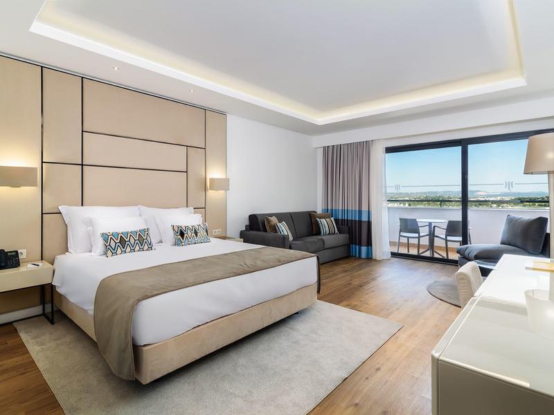 Moderne hotel dakterras met zitgedeeltes en heldere blauwe lucht.