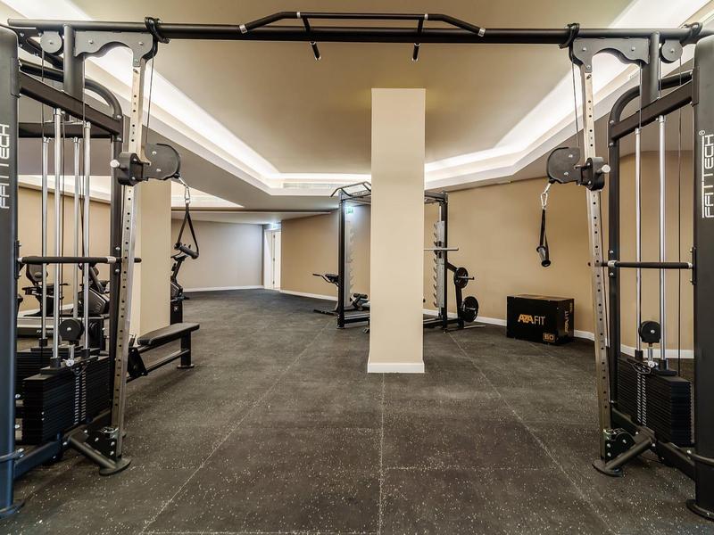 Moderne fitnessruimte met apparatuur en neutrale kleuren, ideaal voor hotelgasten.