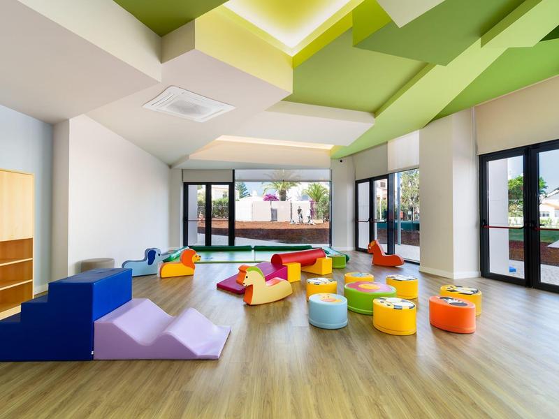 Moderne speelruimte met kleurrijke zitzakken en klimtrappen, grote ramen, heldere sfeer.