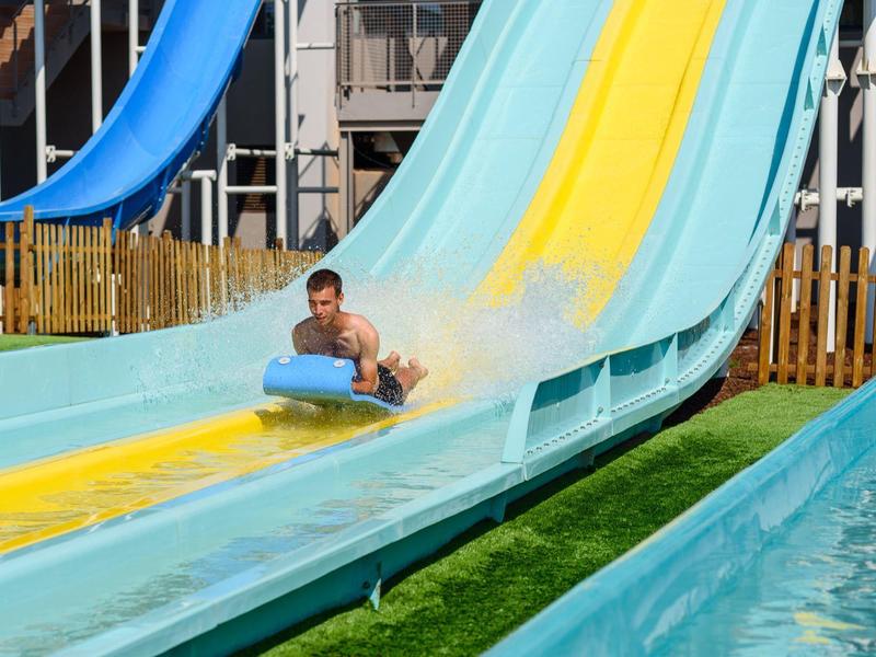 Man rijdt van een waterglijbaan in een waterpark of hotelzwembad.