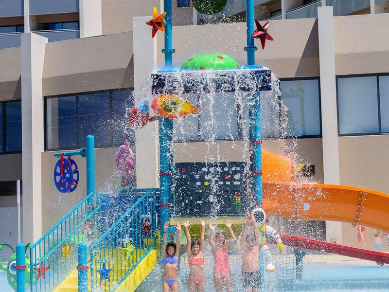Kleurrijke glijbaan met spattend water voor hoog gebouw in vakantieoord.