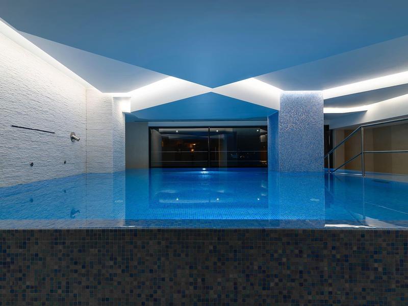 Moderne, verlichte binnenzwembad met helder water en minimalistisch ontwerp.