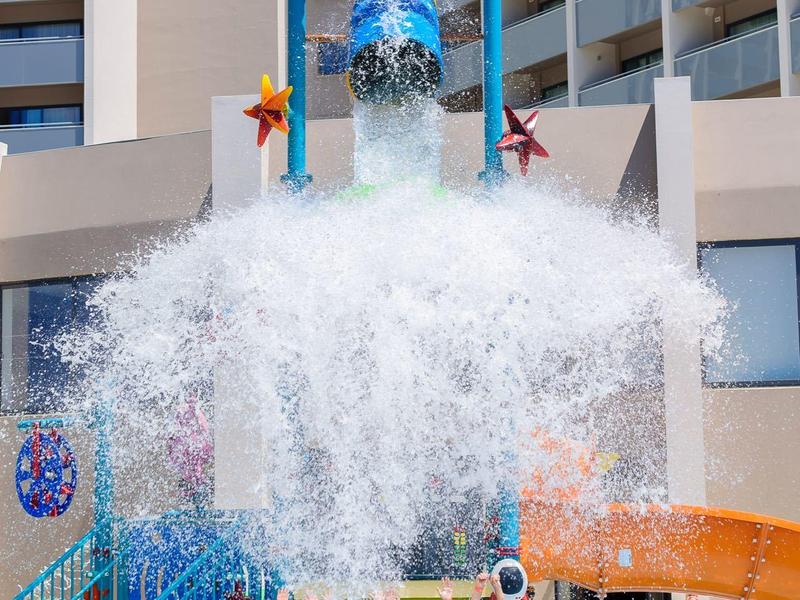 Kinderen staan in het zwembad terwijl een grote emmer water over hen wordt gekiept.