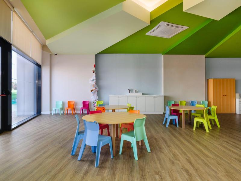 Kleurrijke speelruimte voor kinderen met kleine stoelen en tafels in een kamer met houten vloer.