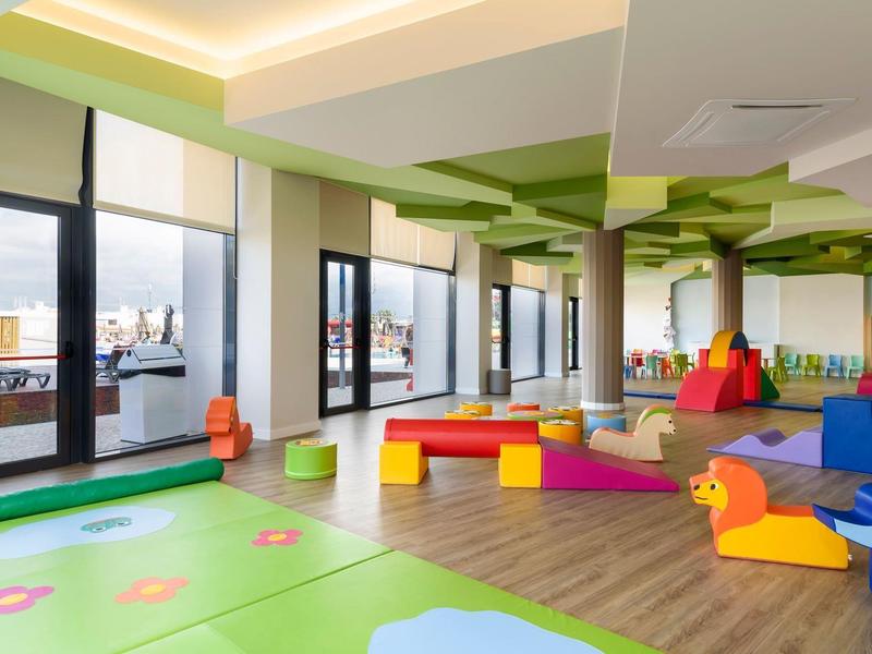 Lichte en kleurrijke speelhoek voor kinderen met grote ramen en uitzicht op de stad.