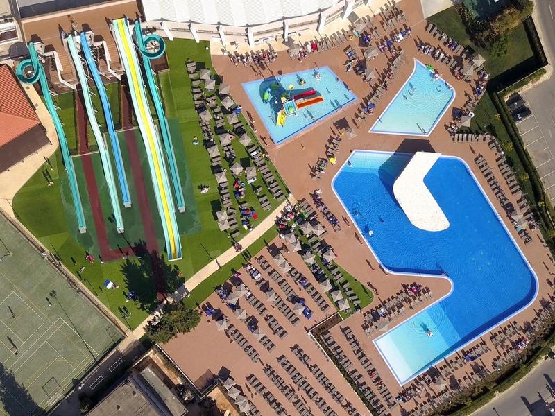 Luchtfoto van een waterpark met meerdere glijbanen en grote zwembaden.