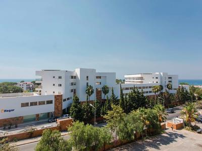 Modern wit hotelcomplex met palmbomen, groen en de zee op de achtergrond