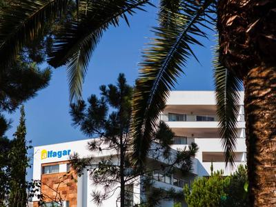 Gebouw met "Singaar" bord achter palmbomen onder een heldere blauwe lucht.