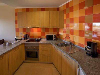 Moderne keuken met kleurrijke oranje-rode tegels en houten kasten.