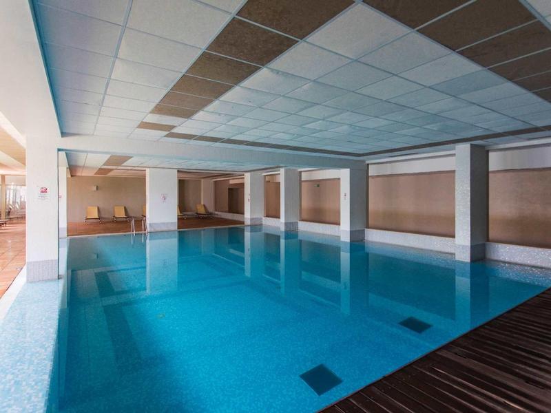 Overdekt zwembad met helder blauw water en modern plafond in een hotel.