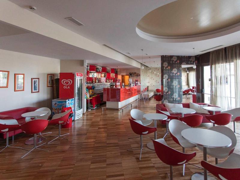 Moderne ontbijtruimte met rode en witte stoelen en houten vloer.