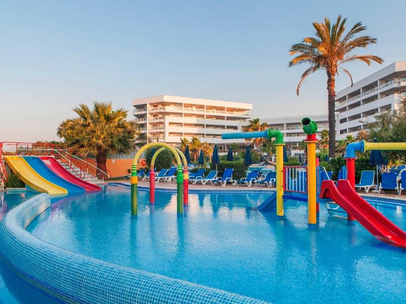 Waterpark met glijbanen en waterspeeltoestellen voor hotelgebouwen bij heldere lucht.